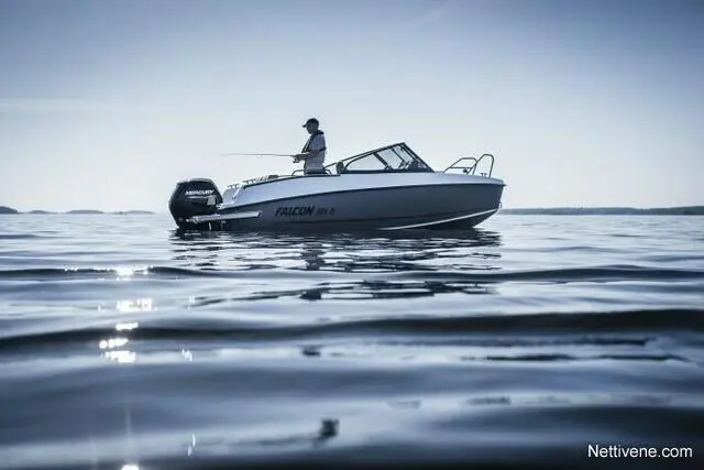 A person fishing from a white Falcon boat, surrounded by calm water under a clear sky.